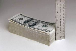 measuring a stack of dollar bills with a ruler